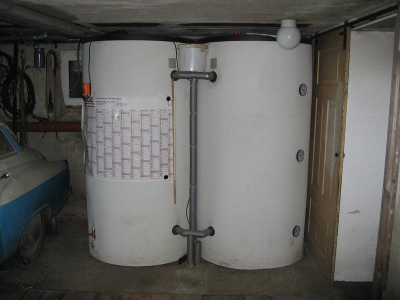 Twee grote witte buffervaten van een verwarmingsinstallatie in een kelder