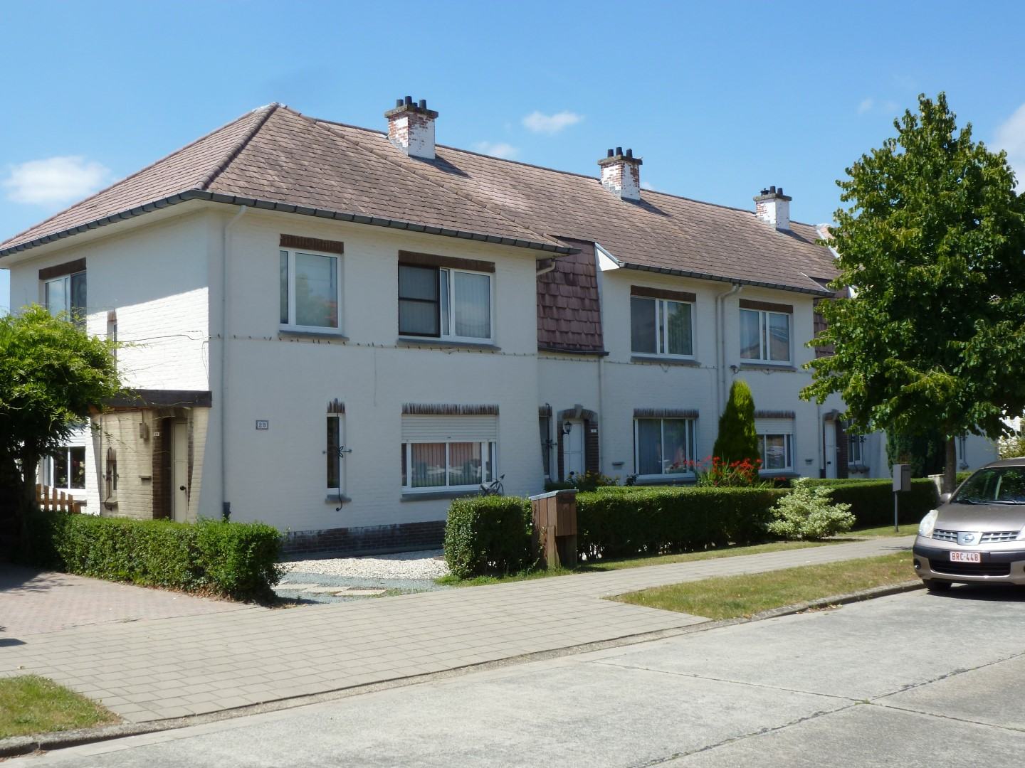 Een rij witte woningen met schoorstenen aan de Bruggelanden in Duffel