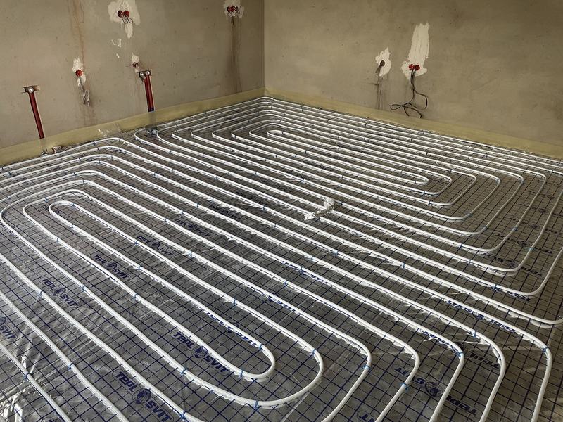 Witte buizen voor vloerverwarming in lussen op isolatieplaten in een lege kamer