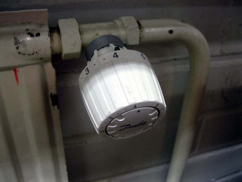 Een thermostatische radiatorkraan met cijfers op een oude radiator